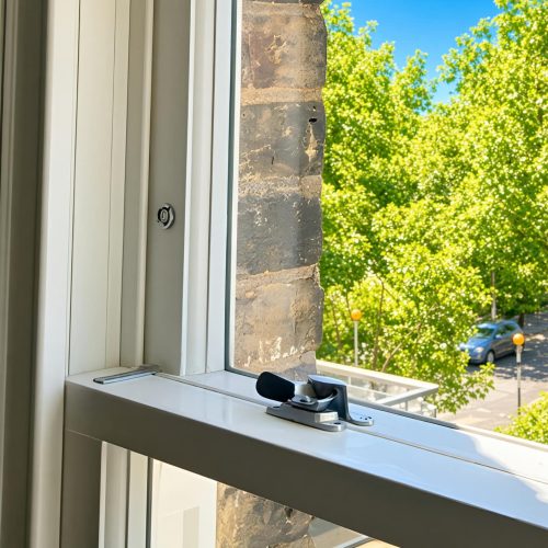 Window restrictor fitted to a timber sash window for controlled opening.