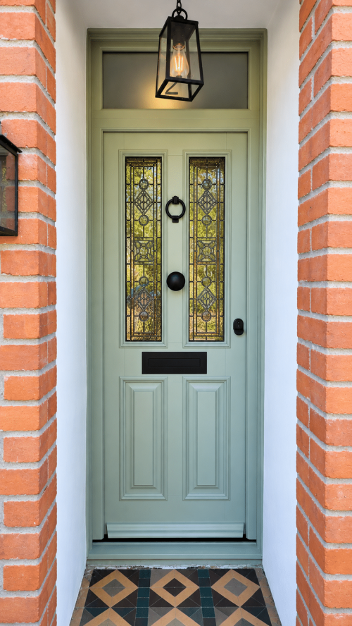 Timber front door with black ironmongery and stained glass panels