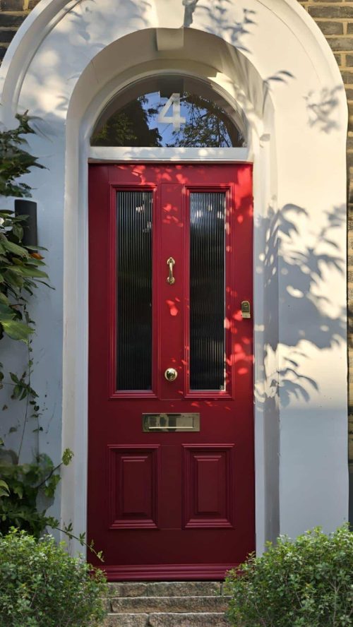 Victorian-style red timber front doors with reeded glass panels and brass hardware.