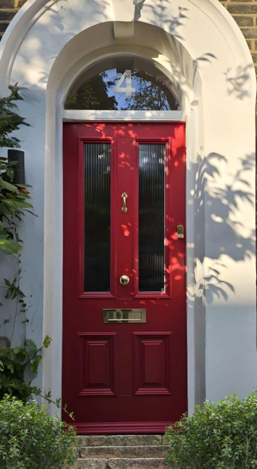 Victorian-style red timber front doors with reeded glass panels and brass hardware.